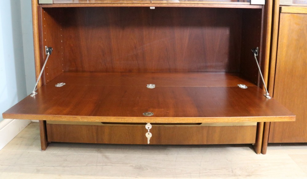 A pair of mid-century teak display cabinets featuring upper sliding glass doors, internal shelving, lower wooden cupboards, drawers, and brass fittings. View VI