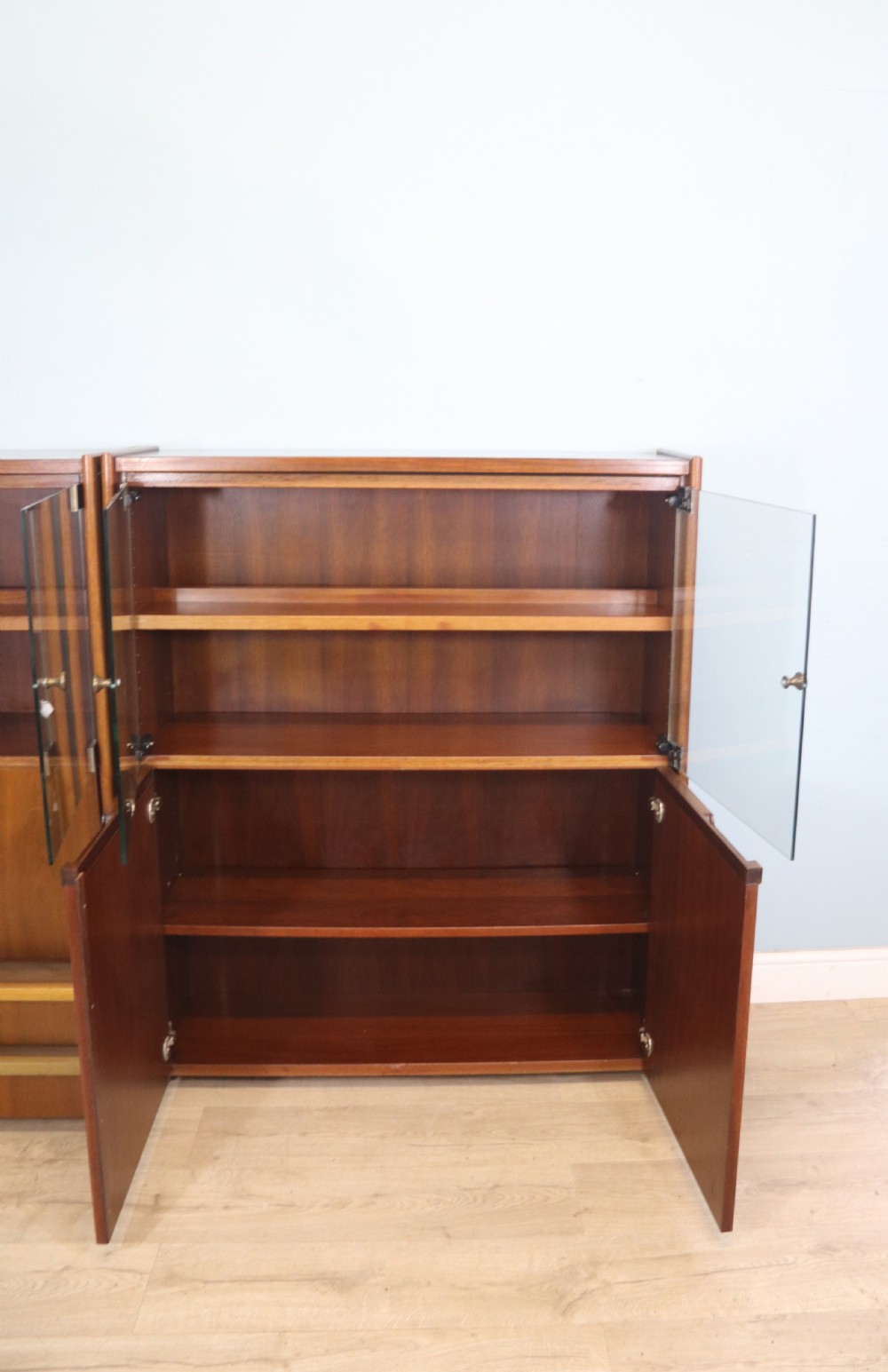 A pair of mid-century teak display cabinets featuring upper sliding glass doors, internal shelving, lower wooden cupboards, drawers, and brass fittings. View XIII