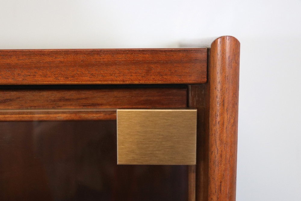 A pair of mid-century teak display cabinets featuring upper sliding glass doors, internal shelving, lower wooden cupboards, drawers, and brass fittings. View XIV