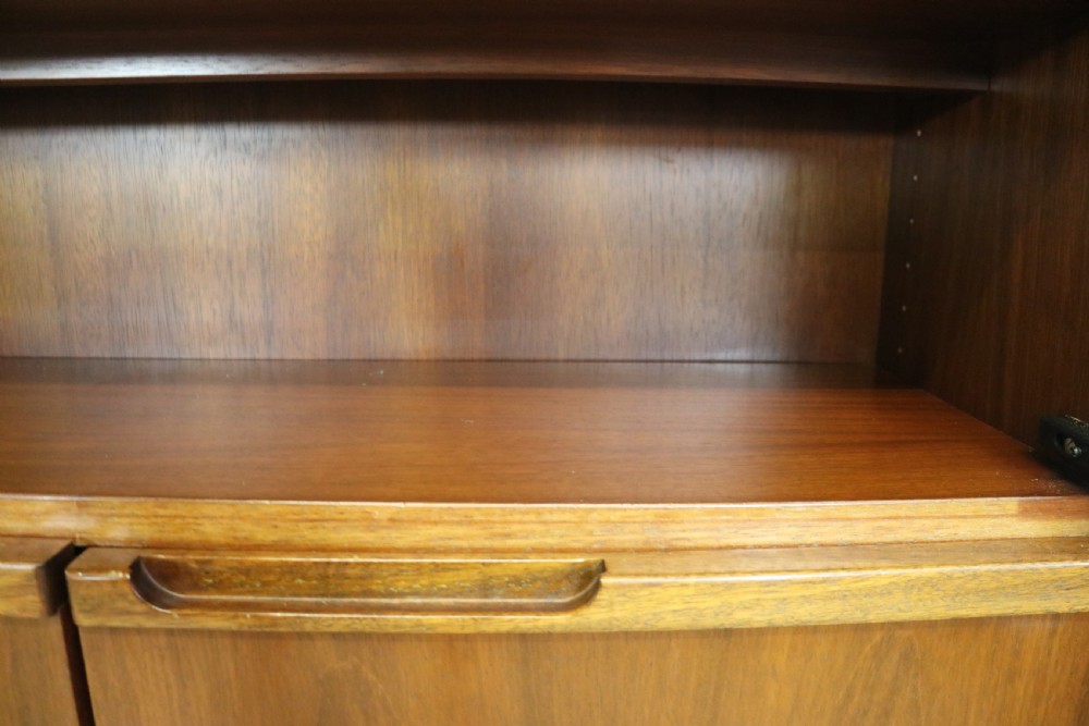 A pair of mid-century teak display cabinets featuring upper sliding glass doors, internal shelving, lower wooden cupboards, drawers, and brass fittings. View XVI