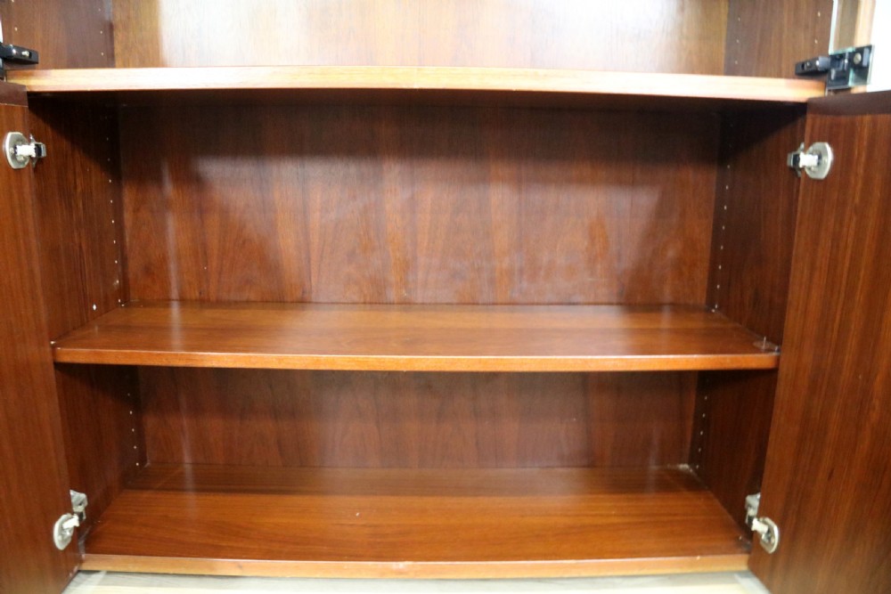 A pair of mid-century teak display cabinets featuring upper sliding glass doors, internal shelving, lower wooden cupboards, drawers, and brass fittings. View XVIII
