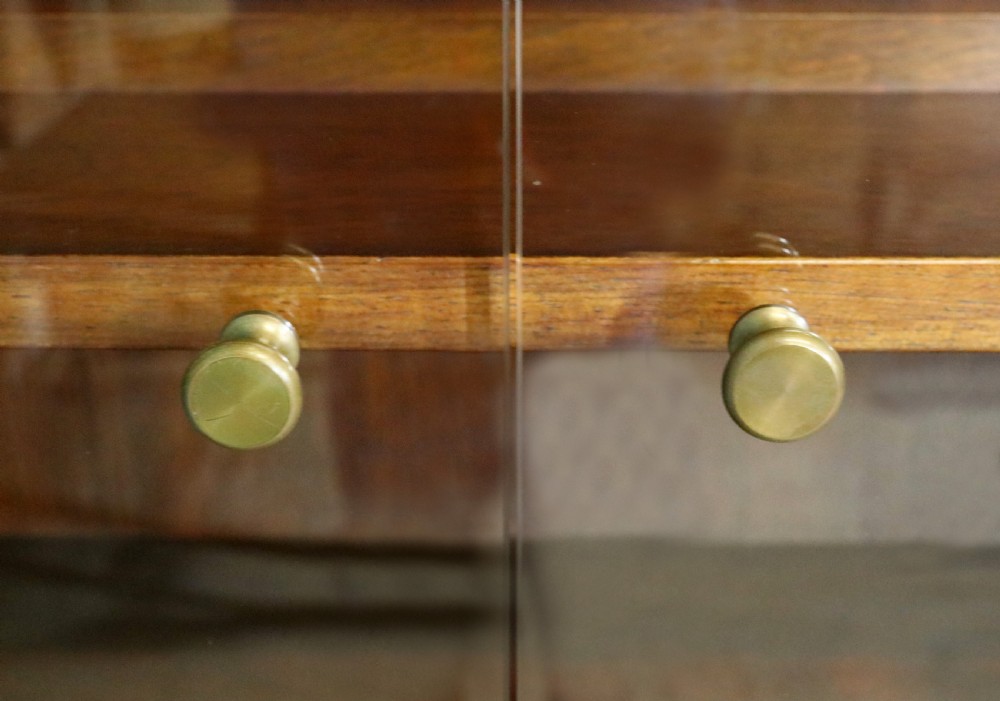 A pair of mid-century teak display cabinets featuring upper sliding glass doors, internal shelving, lower wooden cupboards, drawers, and brass fittings. View XXI