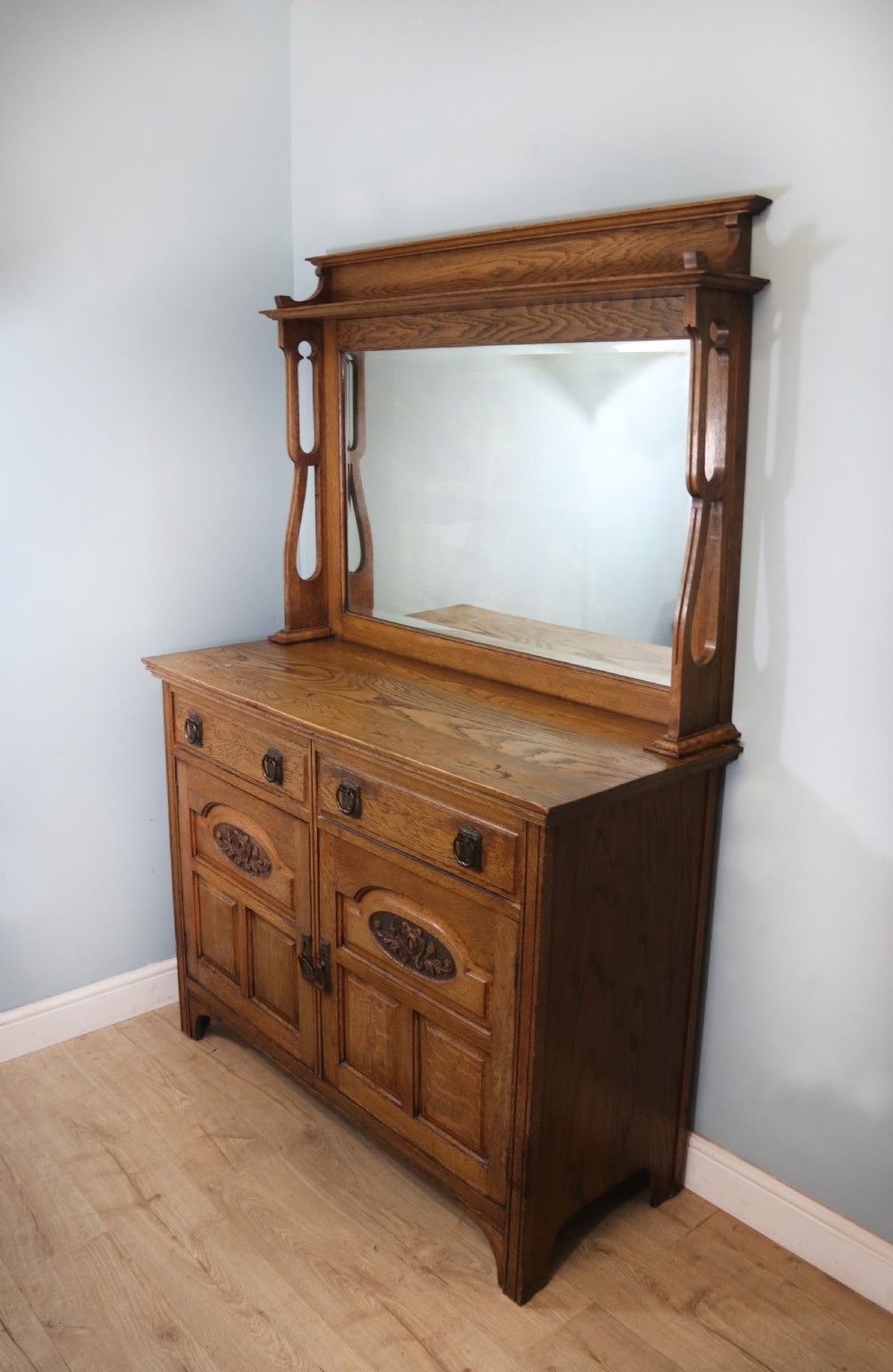 A late Victorian oak sideboard featuring a mirrored upper shelf, two drawers, and two carved panel cupboard doors. View II