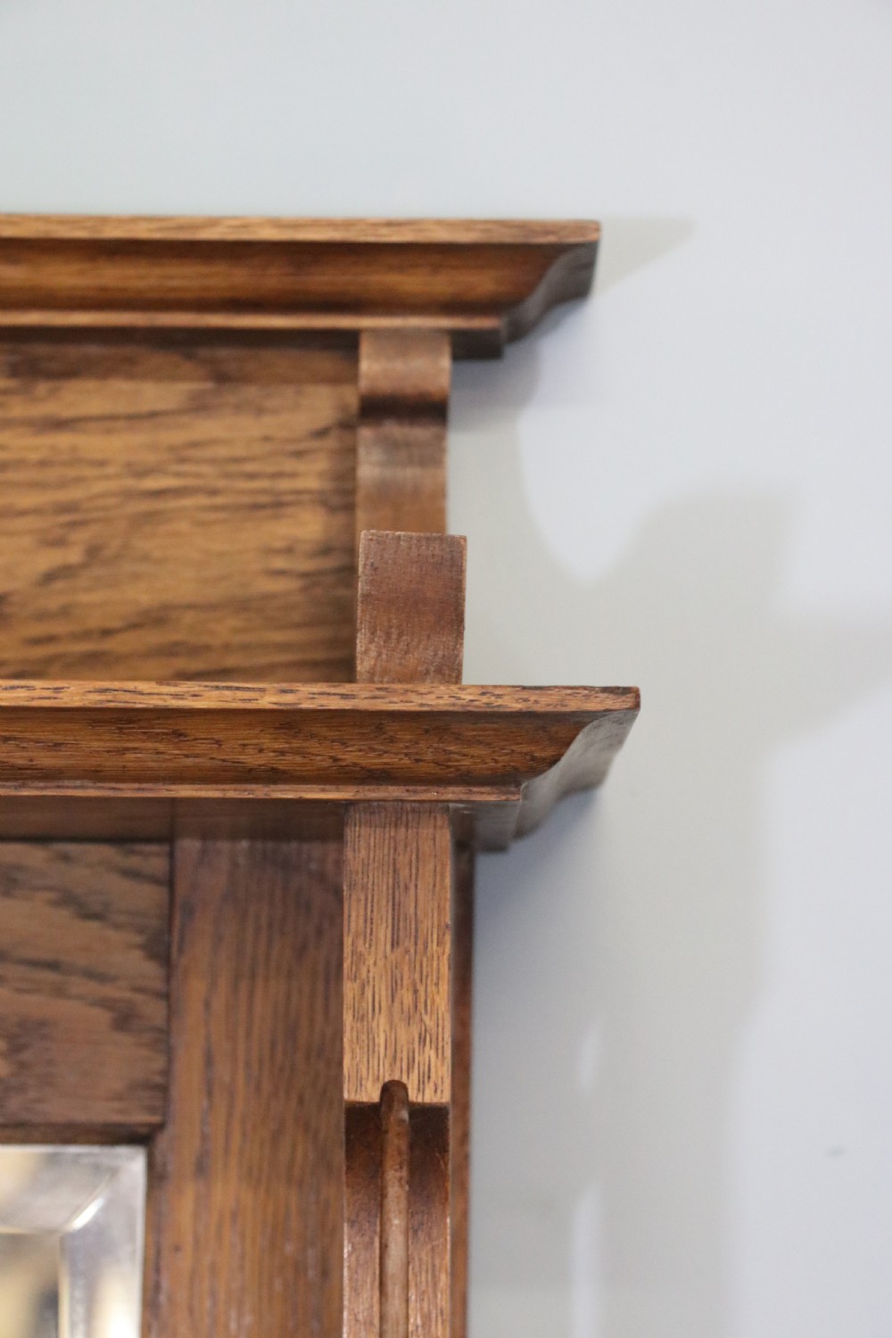 A late Victorian oak sideboard featuring a mirrored upper shelf, two drawers, and two carved panel cupboard doors. View V