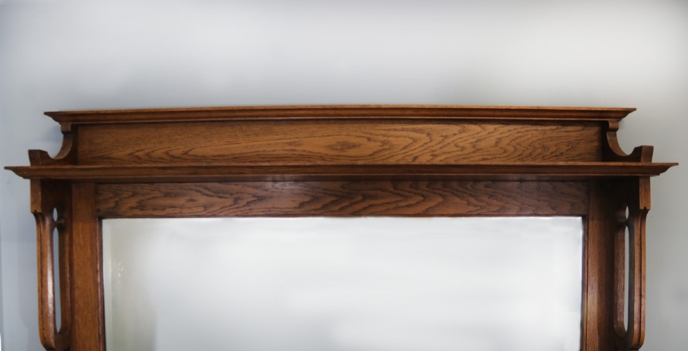 A late Victorian oak sideboard featuring a mirrored upper shelf, two drawers, and two carved panel cupboard doors. View VI