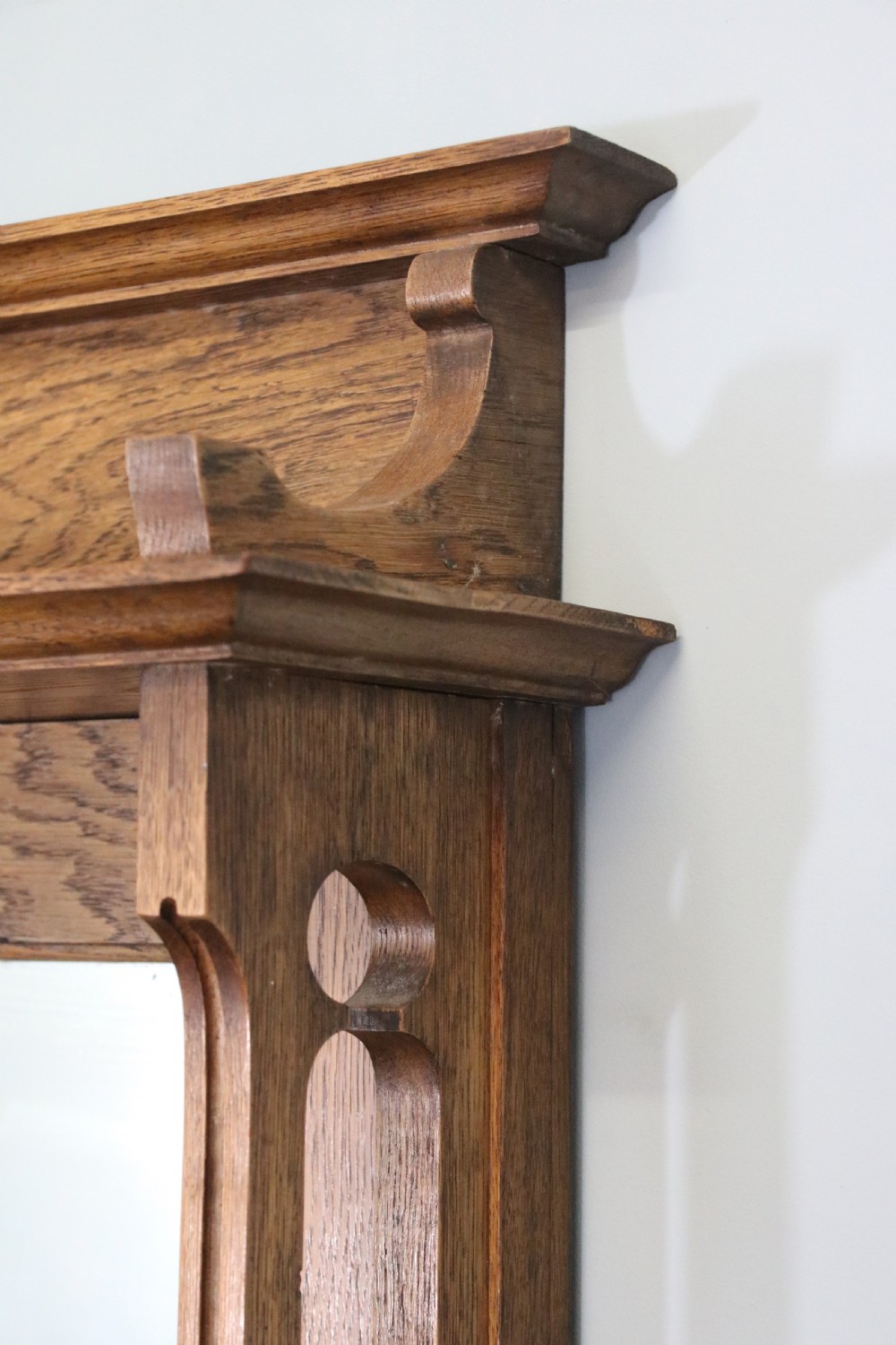 A late Victorian oak sideboard featuring a mirrored upper shelf, two drawers, and two carved panel cupboard doors. View VII