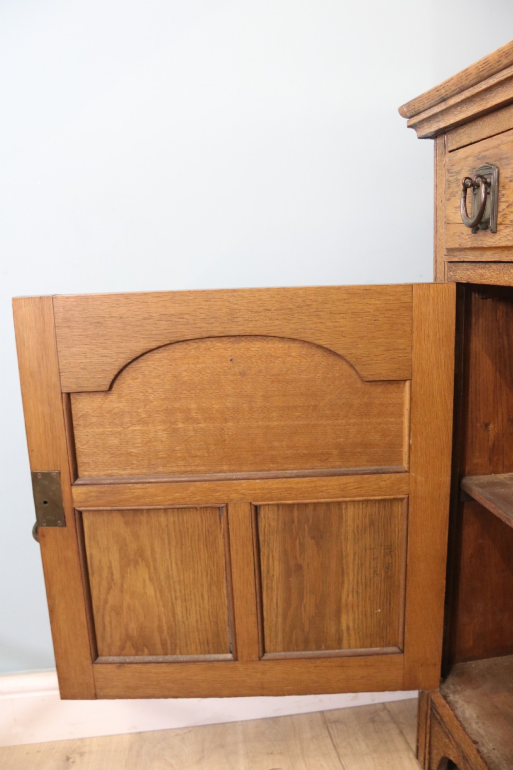 A late Victorian oak sideboard featuring a mirrored upper shelf, two drawers, and two carved panel cupboard doors. View XV