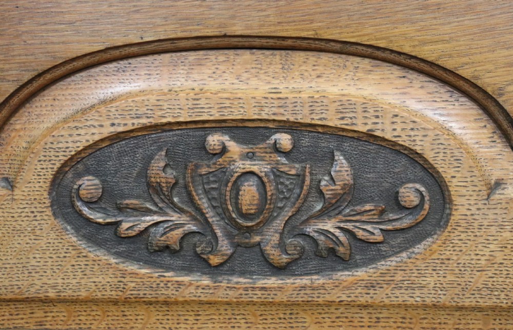 A late Victorian oak sideboard featuring a mirrored upper shelf, two drawers, and two carved panel cupboard doors. View XVII