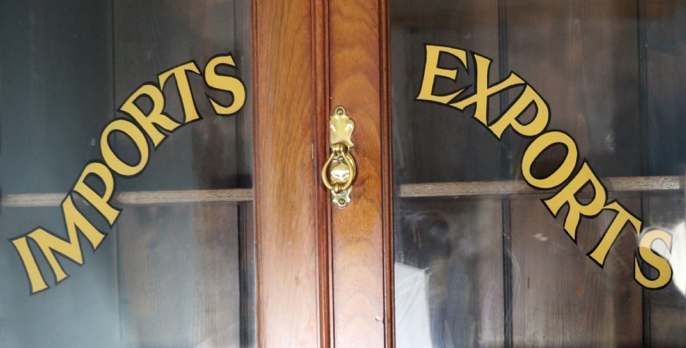 A late 19th-century warm brown walnut glazed bookcase cabinet featuring gilded sign-written trade lettering across the glass doors and lower timber panels. View VI