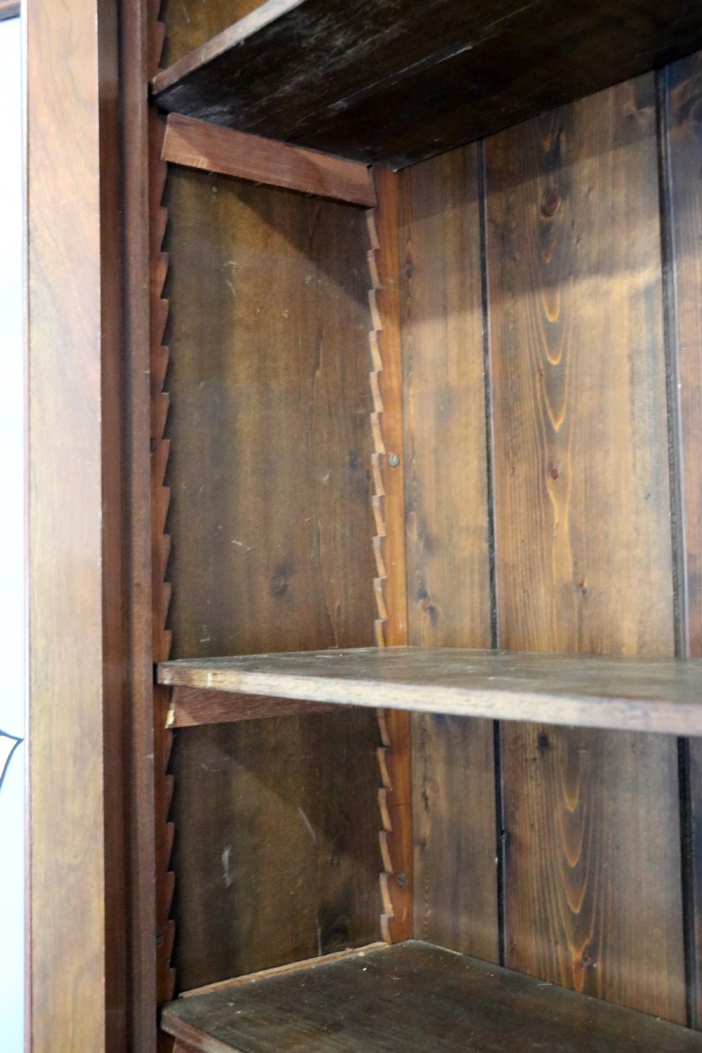 A late 19th-century warm brown walnut glazed bookcase cabinet featuring gilded sign-written trade lettering across the glass doors and lower timber panels. View X