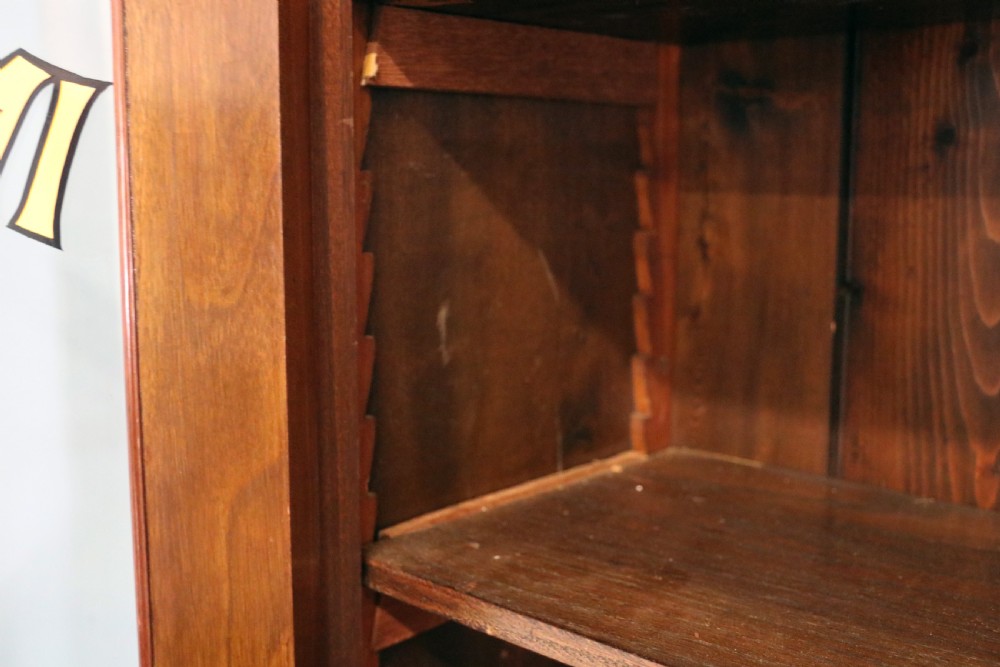 A late 19th-century warm brown walnut glazed bookcase cabinet featuring gilded sign-written trade lettering across the glass doors and lower timber panels. View XI