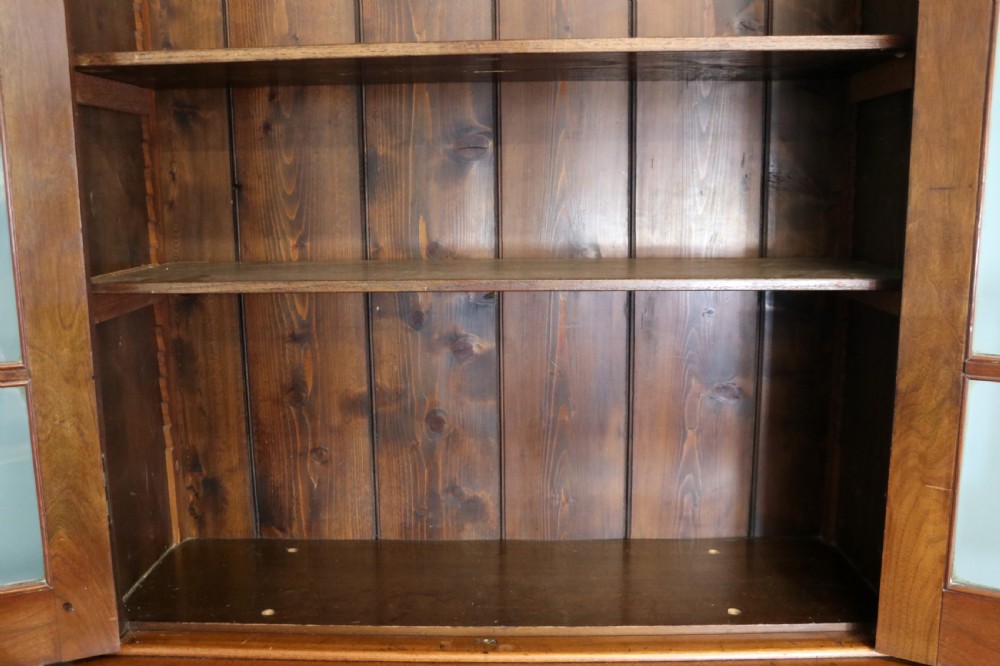 A late 19th-century warm brown walnut glazed bookcase cabinet featuring gilded sign-written trade lettering across the glass doors and lower timber panels. View XIV