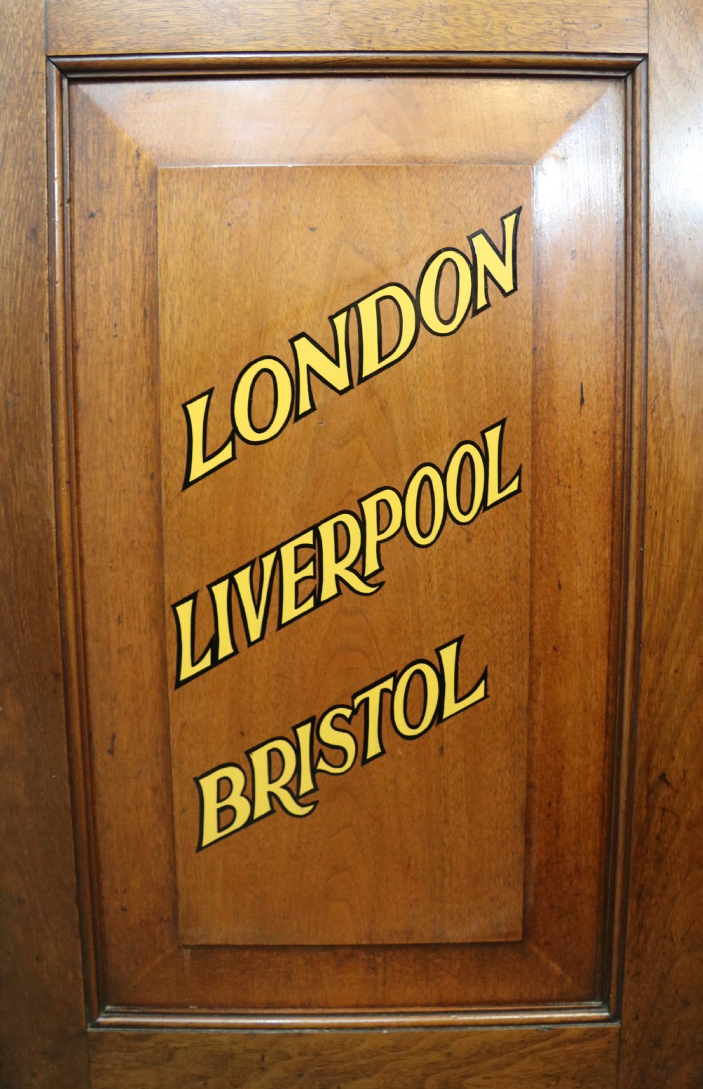 A late 19th-century warm brown walnut glazed bookcase cabinet featuring gilded sign-written trade lettering across the glass doors and lower timber panels. View XVII