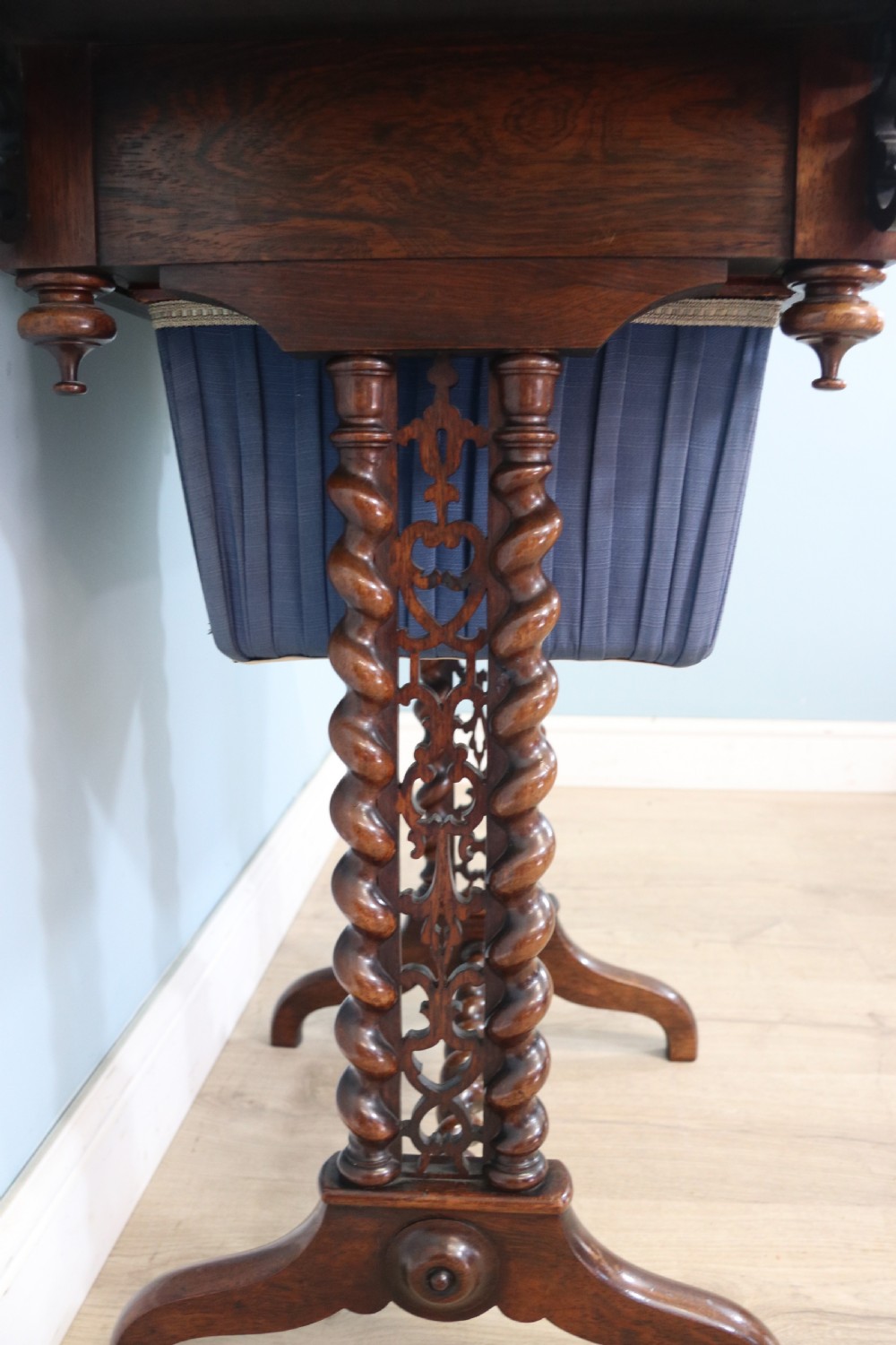A 19th-century dark rosewood sewing table featuring barley twist legs, side fretwork brackets, a single drawer, and a blue fabric work basket below. View VII