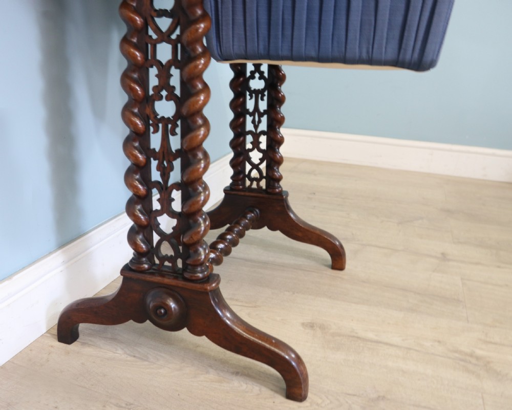 A 19th-century dark rosewood sewing table featuring barley twist legs, side fretwork brackets, a single drawer, and a blue fabric work basket below. View VIII