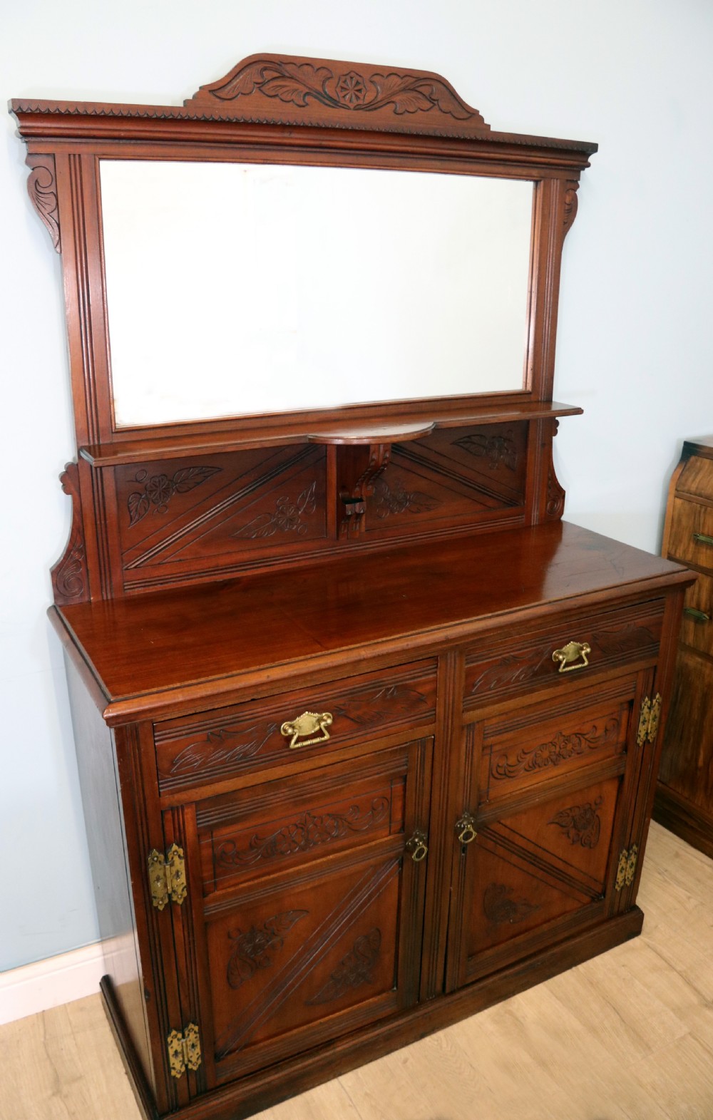 A Victorian American walnut sideboard featuring a mirrored gallery back, carved floral panels, two upper drawers, and two lower cupboard doors. View II
