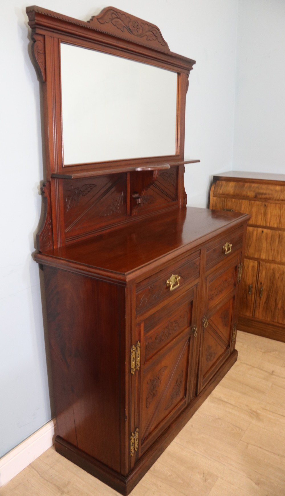 A Victorian American walnut sideboard featuring a mirrored gallery back, carved floral panels, two upper drawers, and two lower cupboard doors. View III