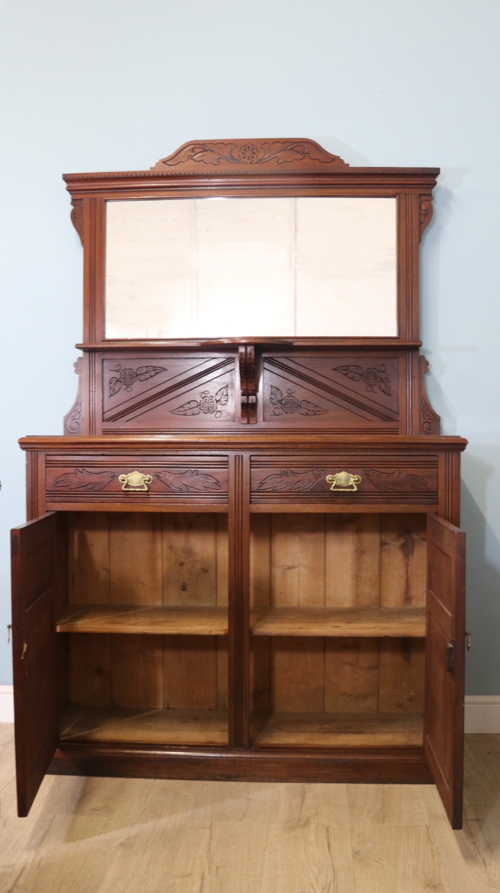 A Victorian American walnut sideboard featuring a mirrored gallery back, carved floral panels, two upper drawers, and two lower cupboard doors. View IV