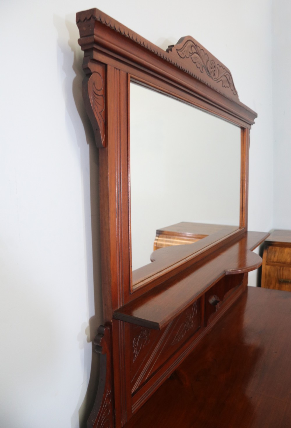 A Victorian American walnut sideboard featuring a mirrored gallery back, carved floral panels, two upper drawers, and two lower cupboard doors. View V