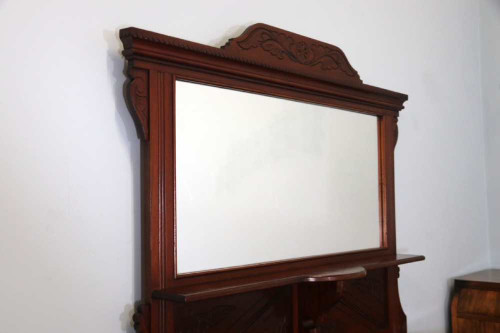 A Victorian American walnut sideboard featuring a mirrored gallery back, carved floral panels, two upper drawers, and two lower cupboard doors. View VI