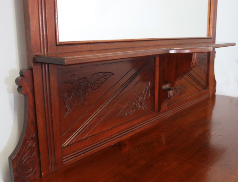 A Victorian American walnut sideboard featuring a mirrored gallery back, carved floral panels, two upper drawers, and two lower cupboard doors. View IX