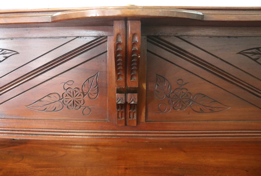 A Victorian American walnut sideboard featuring a mirrored gallery back, carved floral panels, two upper drawers, and two lower cupboard doors. View XI