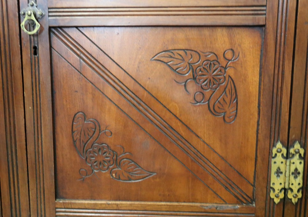 A Victorian American walnut sideboard featuring a mirrored gallery back, carved floral panels, two upper drawers, and two lower cupboard doors. View XVIII