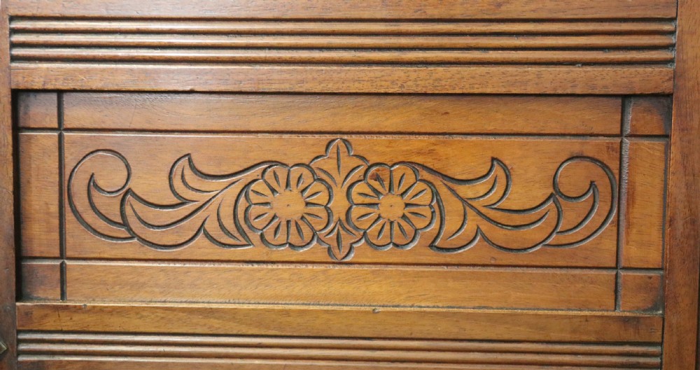 A Victorian American walnut sideboard featuring a mirrored gallery back, carved floral panels, two upper drawers, and two lower cupboard doors. View XIX