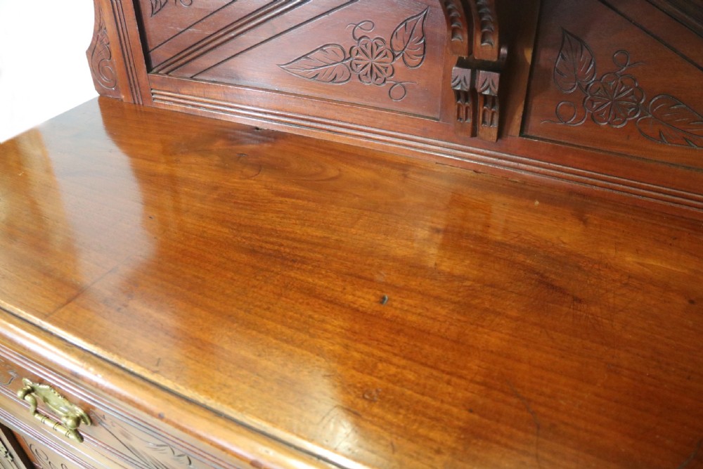A Victorian American walnut sideboard featuring a mirrored gallery back, carved floral panels, two upper drawers, and two lower cupboard doors. View XXII
