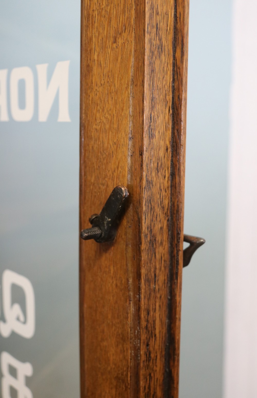 A late nineteenth-century light oak display cabinet featuring glazed upper doors and panelled lower doors decorated with hand-painted white commercial signage. View XIV