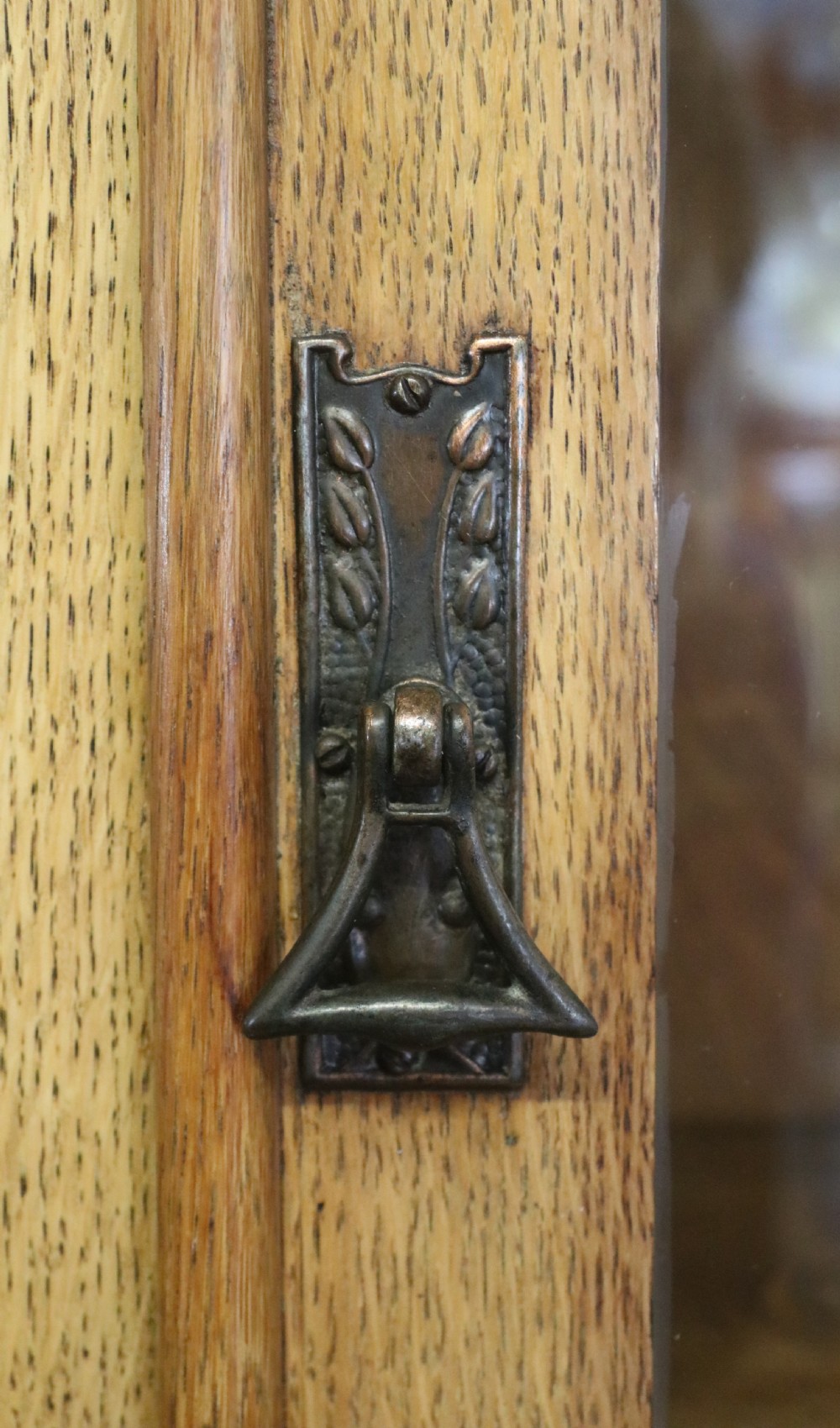 A late nineteenth-century light oak display cabinet featuring glazed upper doors and panelled lower doors decorated with hand-painted white commercial signage. View XV