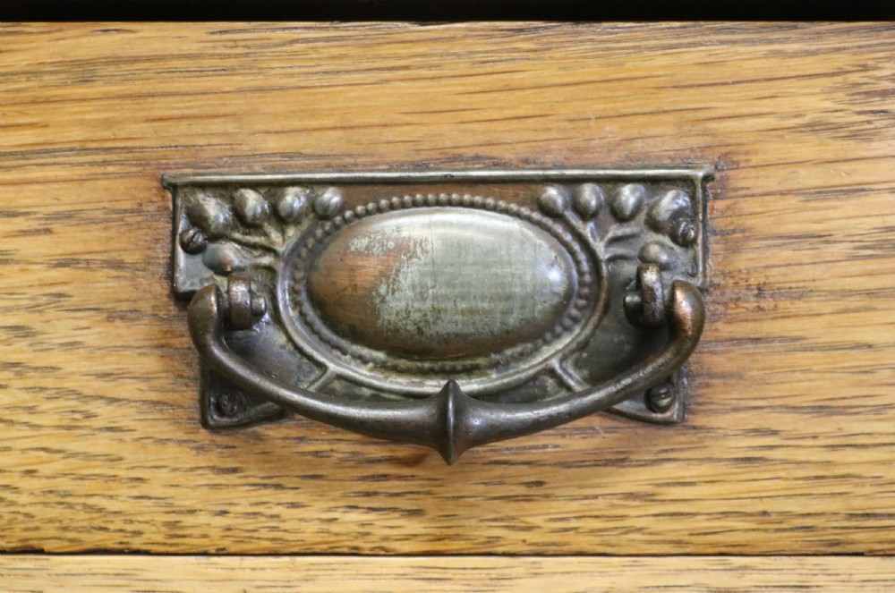 A late nineteenth-century light oak display cabinet featuring glazed upper doors and panelled lower doors decorated with hand-painted white commercial signage. View XIX