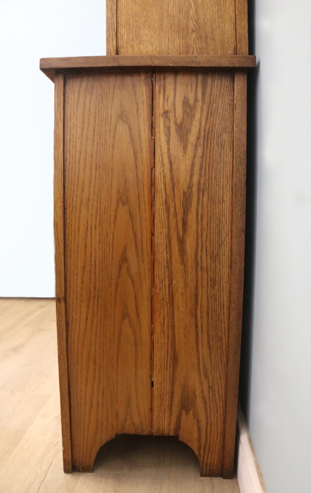A late nineteenth-century light oak display cabinet featuring glazed upper doors and panelled lower doors decorated with hand-painted white commercial signage. View XXIV