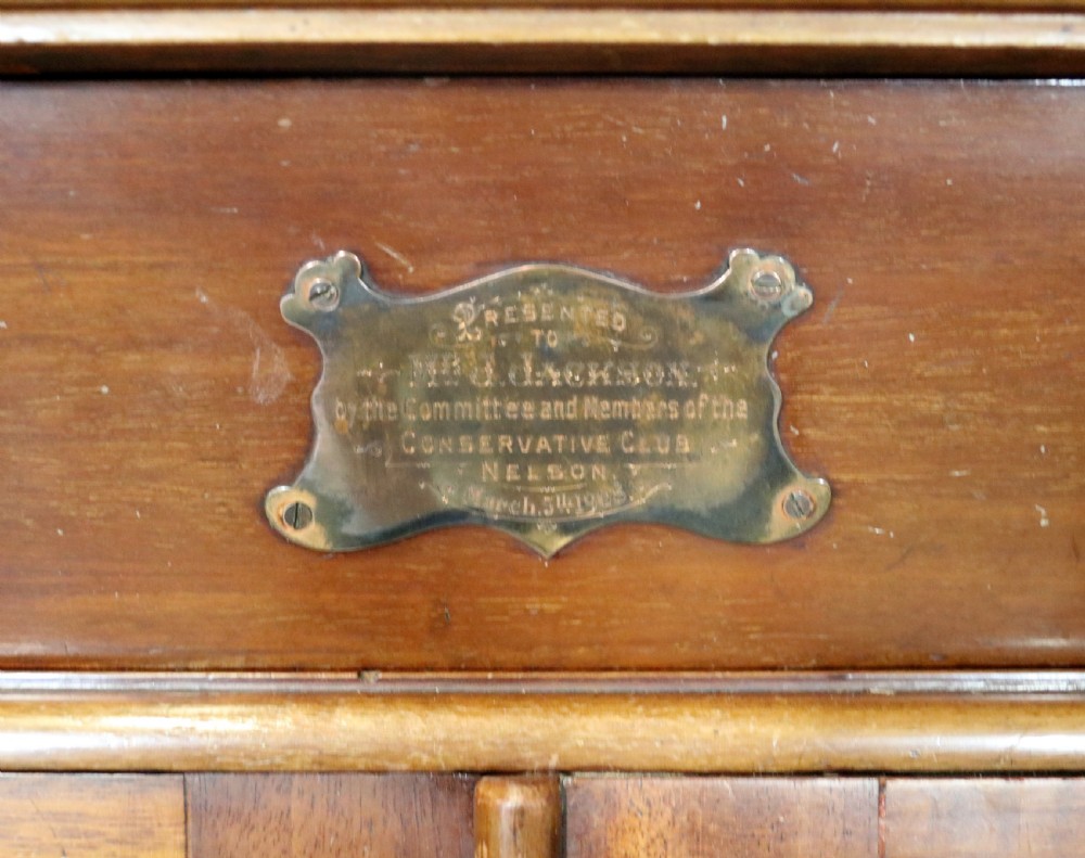 An early 20th-century walnut side cabinet featuring arched leaded glass doors, a top drawer, and two lower drawers with metal handles. View VII