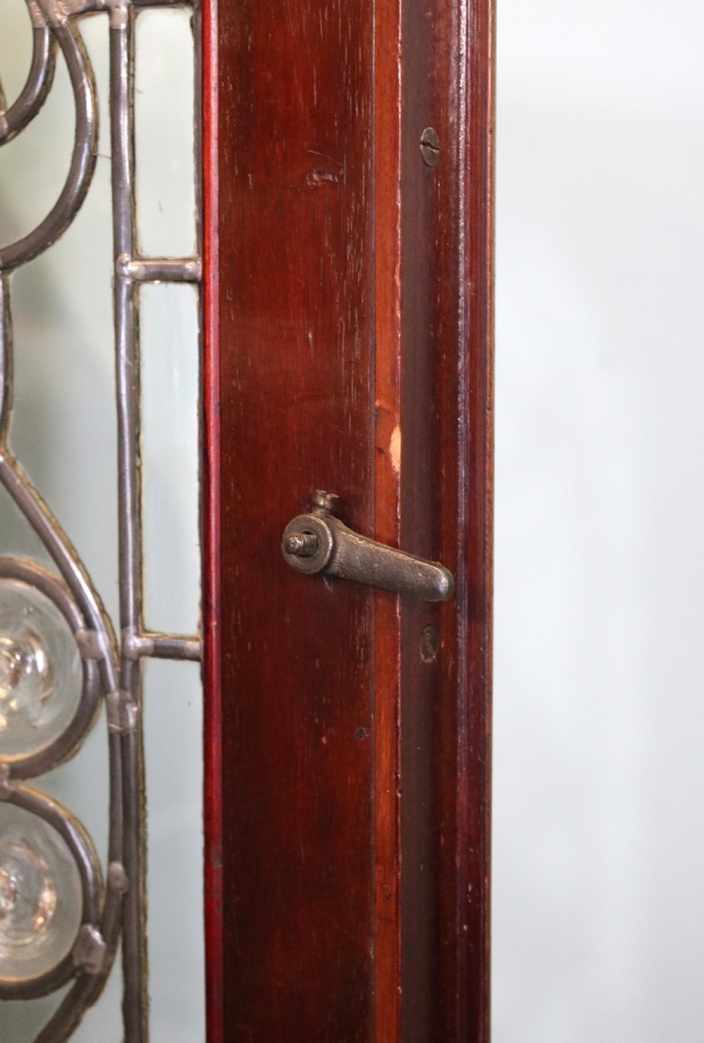 An early 20th-century walnut side cabinet featuring arched leaded glass doors, a top drawer, and two lower drawers with metal handles. View X