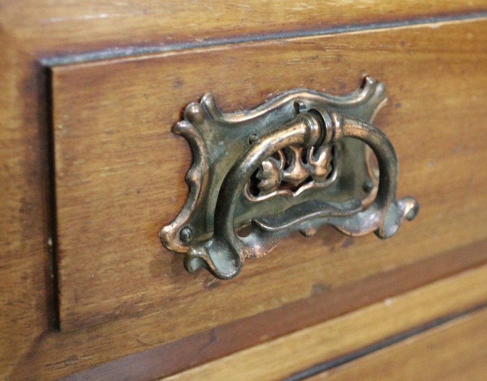 An early 20th-century walnut side cabinet featuring arched leaded glass doors, a top drawer, and two lower drawers with metal handles. View XIV
