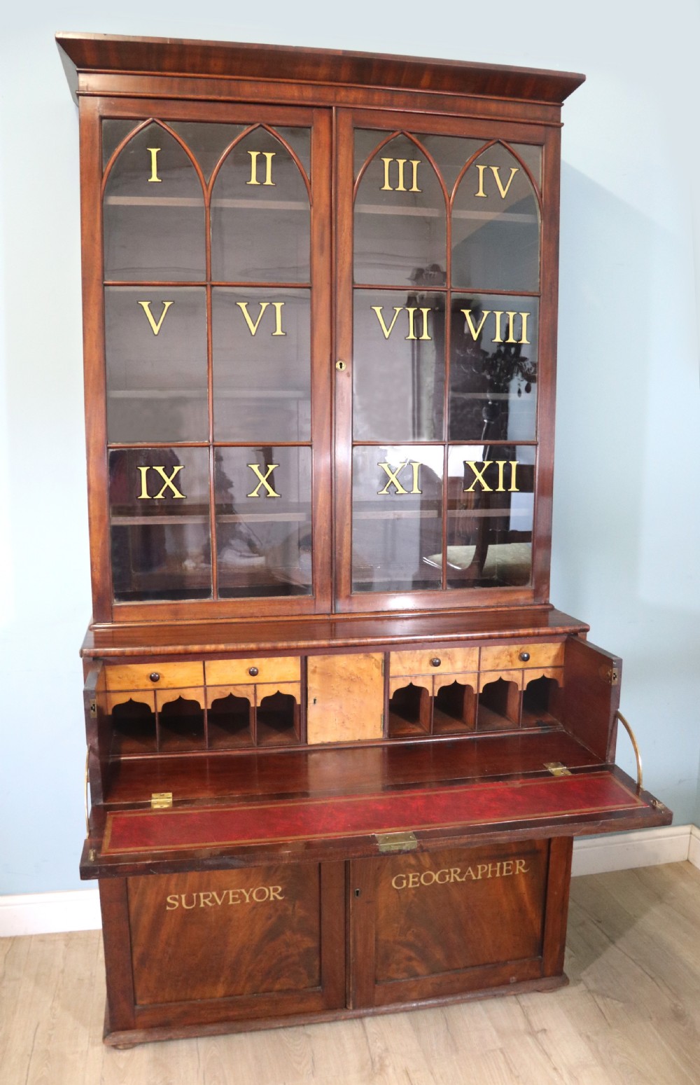 A late Georgian mahogany secretaire bookcase with glazed upper doors featuring Roman numerals, a drop-front fitted writing desk, and two cabinet doors below.