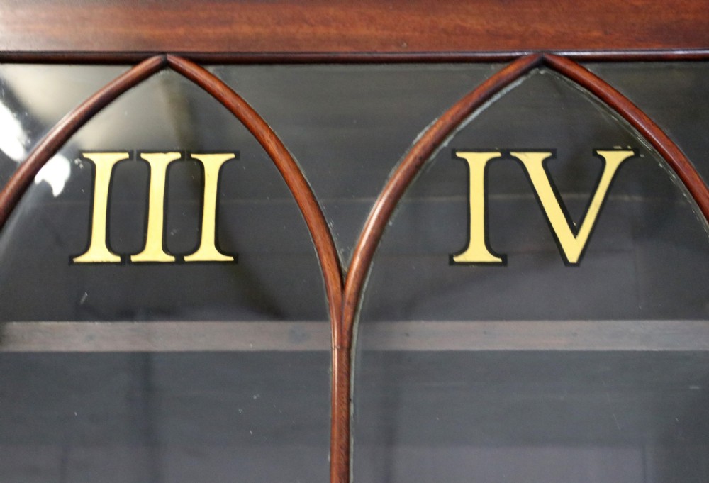 A late Georgian mahogany secretaire bookcase with glazed upper doors featuring Roman numerals, a drop-front fitted writing desk, and two cabinet doors below. View VII