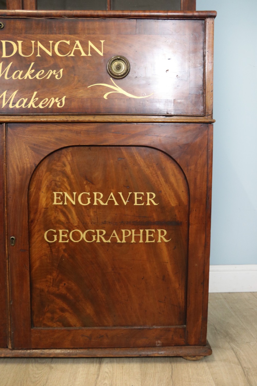 A late Georgian mahogany secretaire bookcase with glazed upper doors featuring Roman numerals, a drop-front fitted writing desk, and two cabinet doors below. View XIII