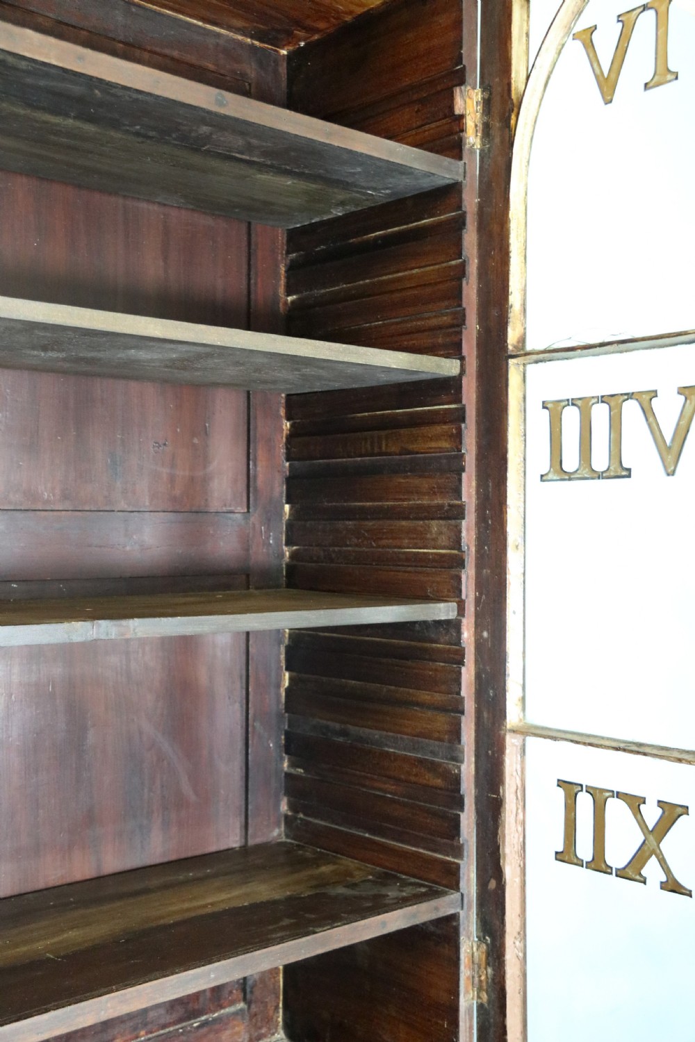 A late Georgian mahogany secretaire bookcase with glazed upper doors featuring Roman numerals, a drop-front fitted writing desk, and two cabinet doors below. View XIX