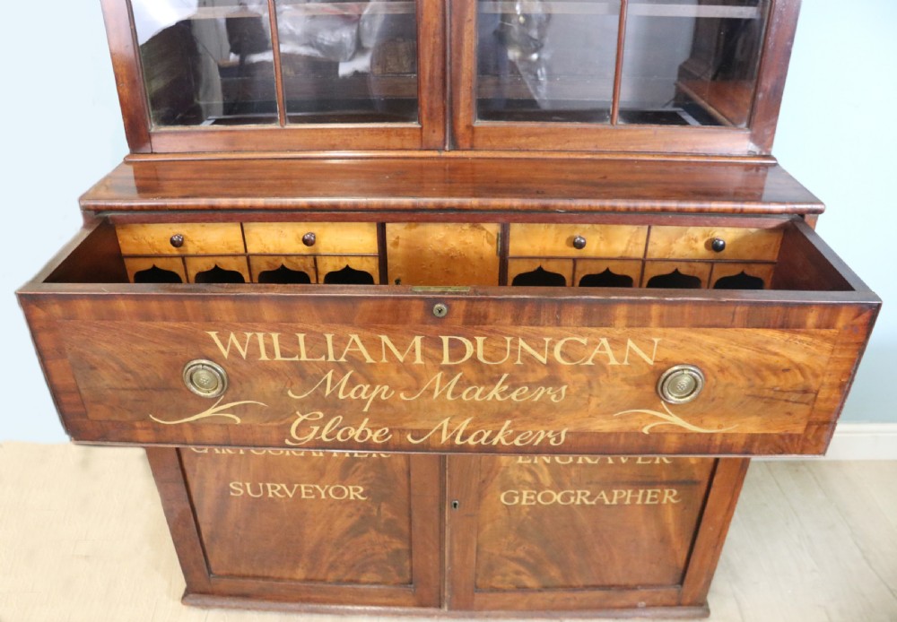 A late Georgian mahogany secretaire bookcase with glazed upper doors featuring Roman numerals, a drop-front fitted writing desk, and two cabinet doors below. View XXI