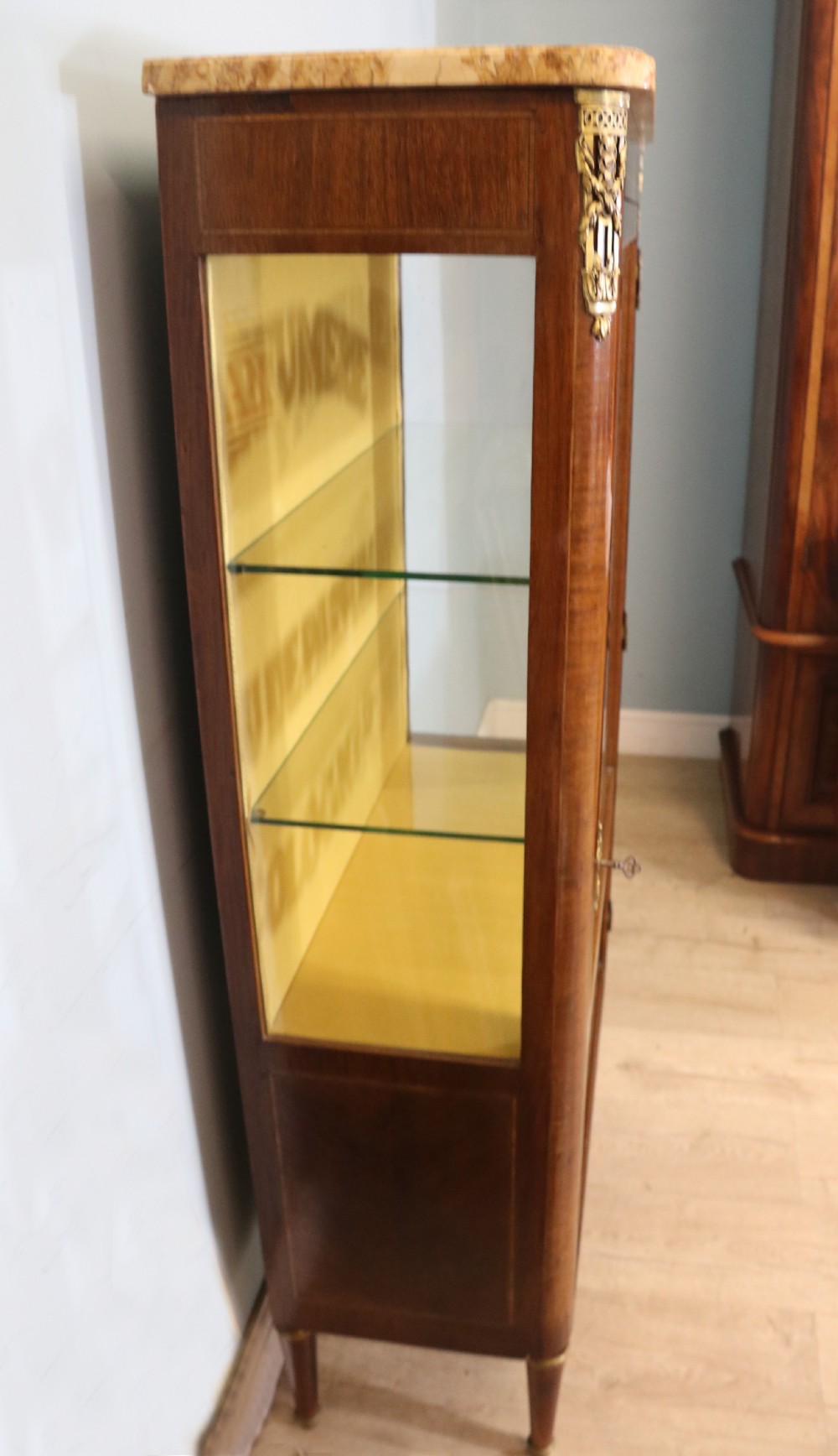 A French mahogany vitrine featuring a marble top, glass display door with gilt perfumery lettering, glass shelves, and brass mounts. View VII