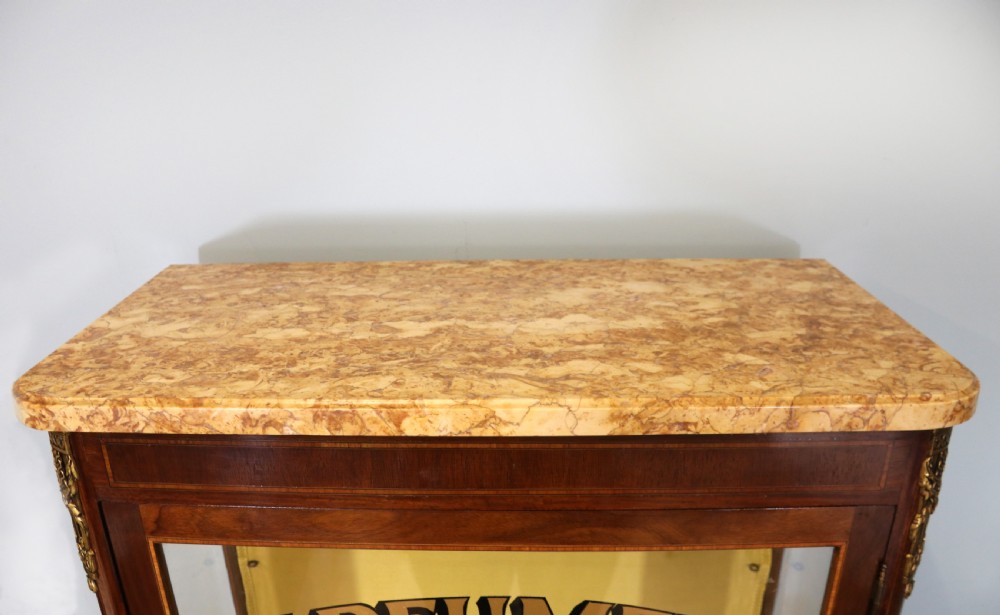 A French mahogany vitrine featuring a marble top, glass display door with gilt perfumery lettering, glass shelves, and brass mounts. View X