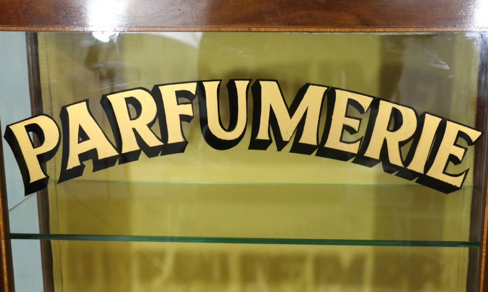 A French mahogany vitrine featuring a marble top, glass display door with gilt perfumery lettering, glass shelves, and brass mounts. View XVI