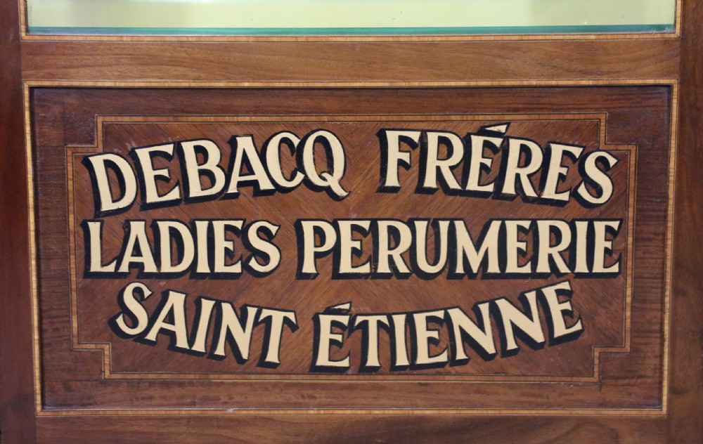 A French mahogany vitrine featuring a marble top, glass display door with gilt perfumery lettering, glass shelves, and brass mounts. View XVIII