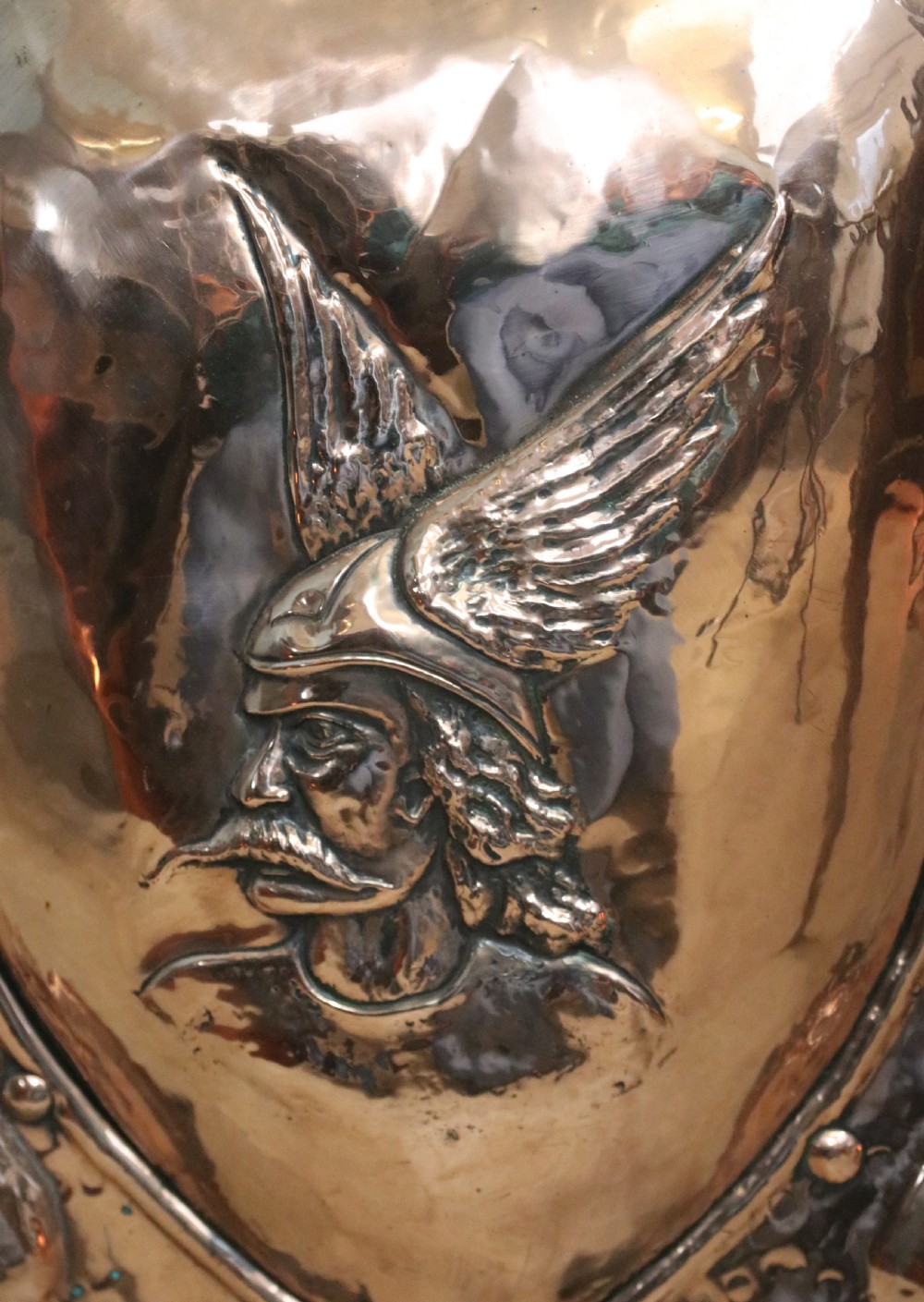 A 19th-century repousse copper panel fire screen featuring a winged warrior profile motif mounted in a wrought-iron frame with splayed feet. View VI