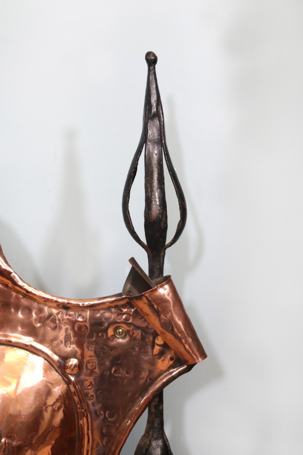 A 19th-century repousse copper panel fire screen featuring a winged warrior profile motif mounted in a wrought-iron frame with splayed feet. View IX