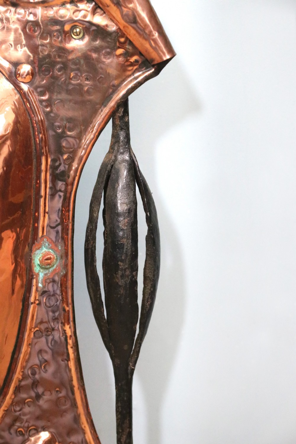 A 19th-century repousse copper panel fire screen featuring a winged warrior profile motif mounted in a wrought-iron frame with splayed feet. View XII
