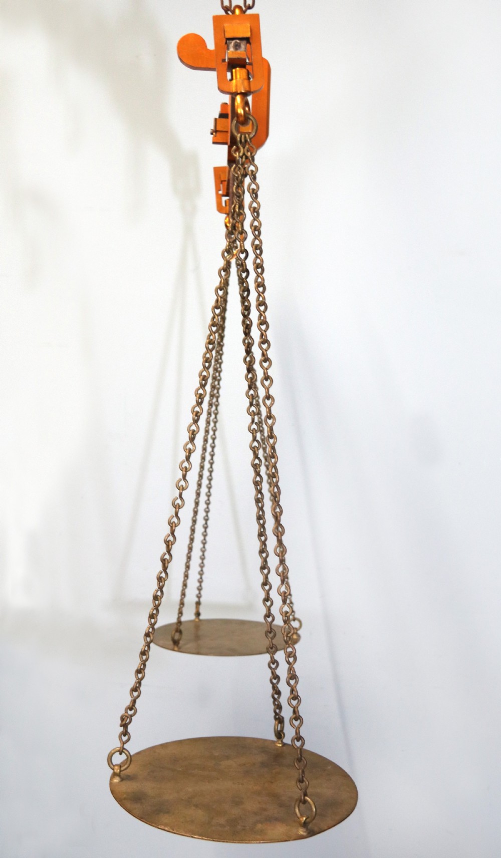 A large hanging brass beam balance scale featuring stamped lettering, suspended chain links, and two circular brass pans. View IV