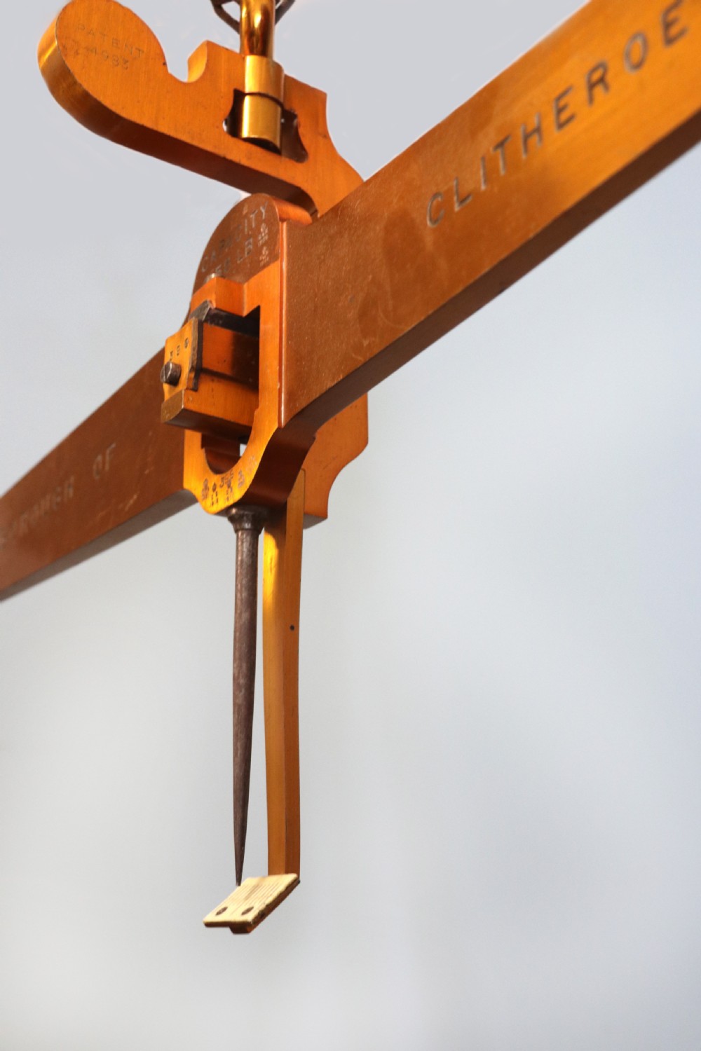 A large hanging brass beam balance scale featuring stamped lettering, suspended chain links, and two circular brass pans. View VII